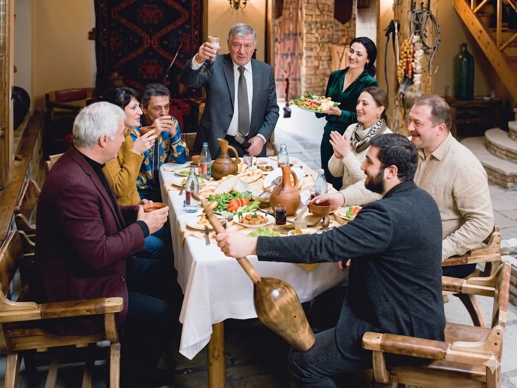 Georgische Tischrunde mit Gästen beim gemeinsamen Essen und Anstoßen in traditioneller Atmosphäre